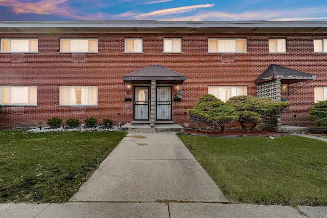 view of front of home featuring brick siding and a front lawn