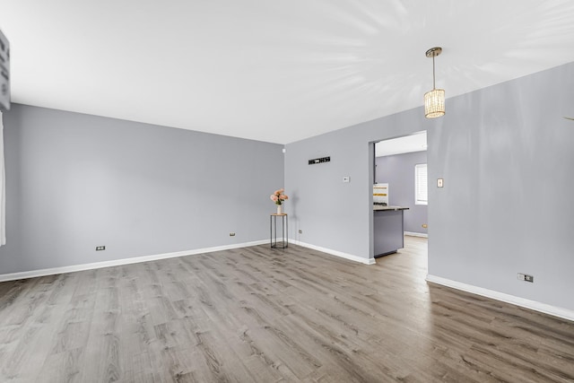 unfurnished living room featuring wood finished floors and baseboards