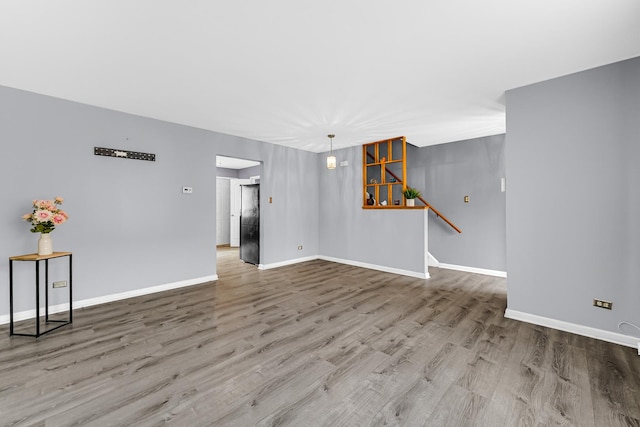 unfurnished living room featuring baseboards and wood finished floors