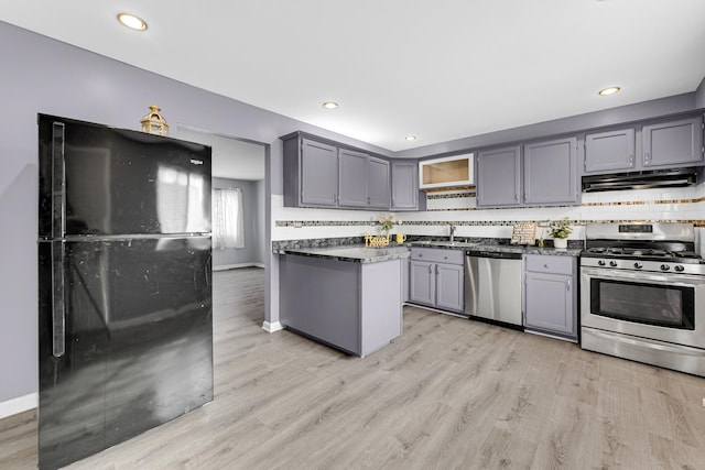 kitchen with decorative backsplash, stainless steel appliances, gray cabinetry, light wood-type flooring, and under cabinet range hood