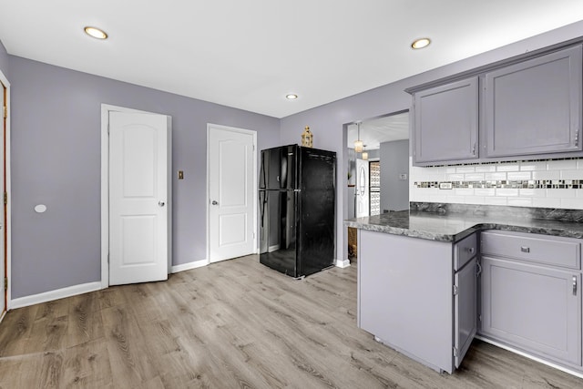 kitchen with baseboards, decorative backsplash, light wood-style flooring, freestanding refrigerator, and gray cabinets