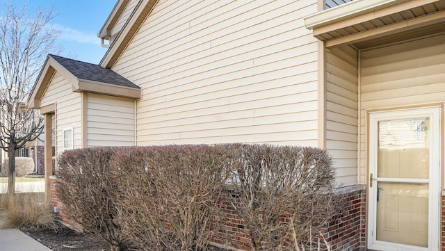 view of side of property with brick siding and a shingled roof