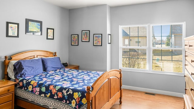 bedroom featuring light wood-style floors, visible vents, and baseboards