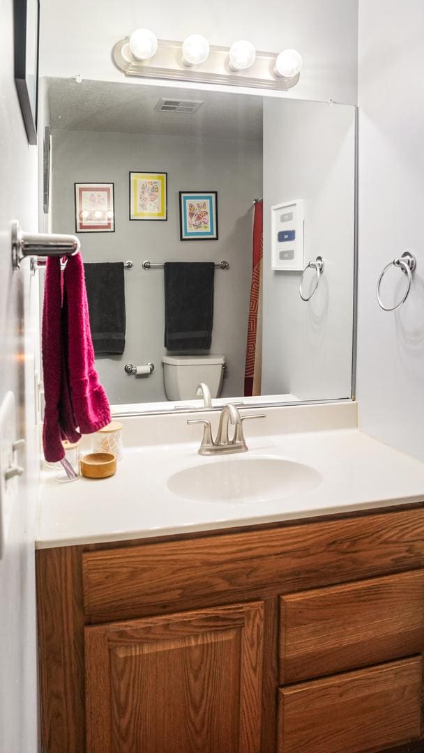 bathroom with visible vents, toilet, and vanity