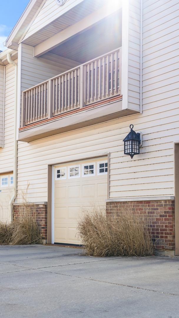 view of property exterior with concrete driveway, a balcony, an attached garage, and brick siding