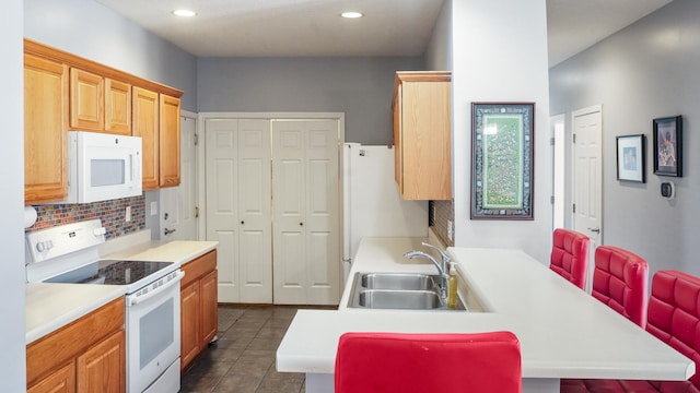 kitchen featuring a sink, white appliances, tasteful backsplash, and a peninsula