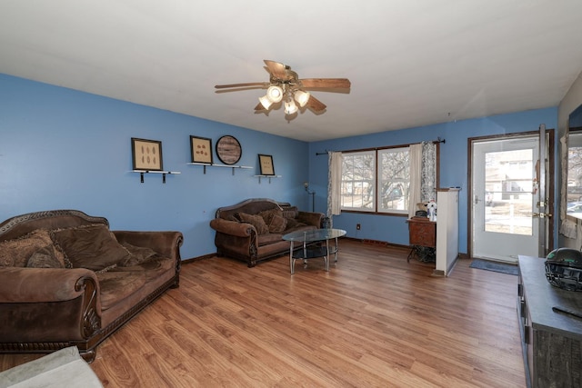 living room with a ceiling fan, baseboards, and light wood finished floors