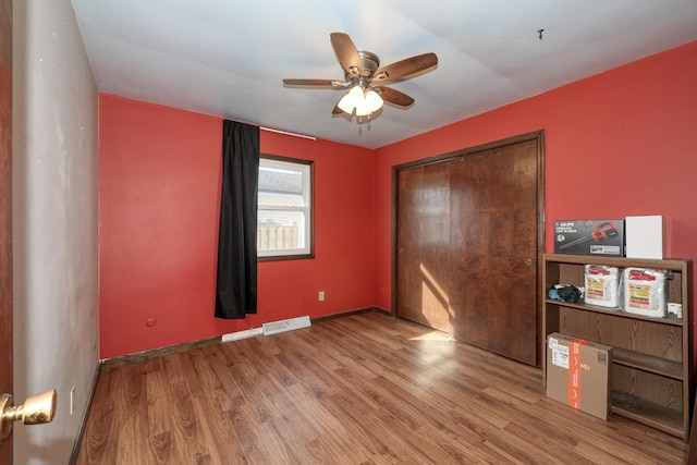 unfurnished bedroom featuring visible vents, wood finished floors, a closet, baseboards, and ceiling fan