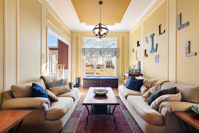 living area with stairs, a chandelier, wood finished floors, and crown molding