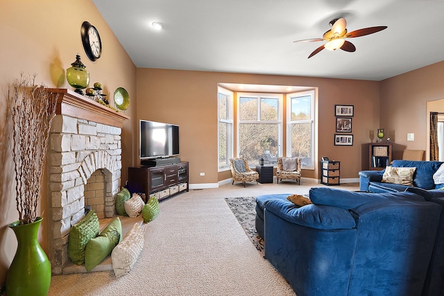 living area with a ceiling fan, carpet flooring, a fireplace with raised hearth, and baseboards