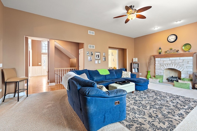 living room featuring a stone fireplace, visible vents, and light colored carpet