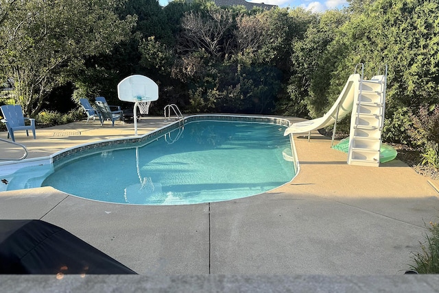 pool featuring a water slide and a patio area