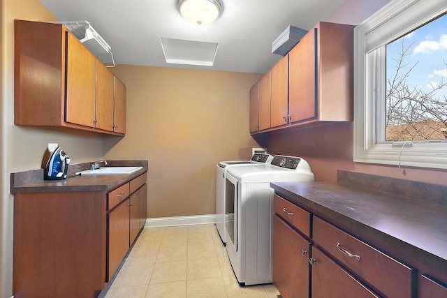 laundry room with light tile patterned floors, cabinet space, a sink, separate washer and dryer, and baseboards