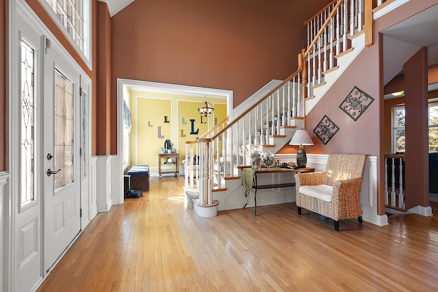 entrance foyer with a decorative wall, a wainscoted wall, a high ceiling, stairs, and hardwood / wood-style floors