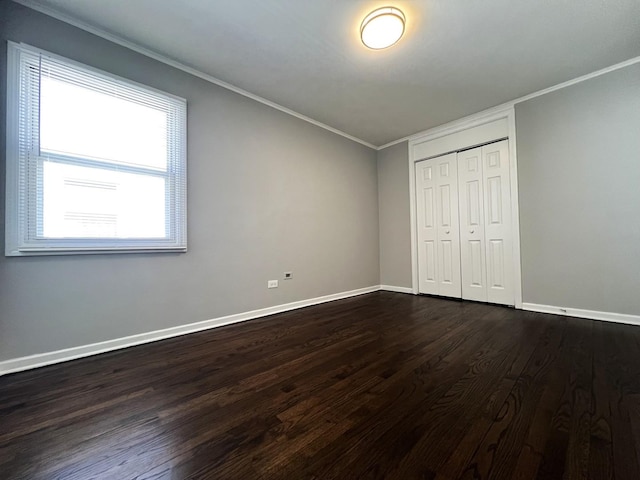 unfurnished bedroom with dark wood-style floors, baseboards, ornamental molding, and a closet