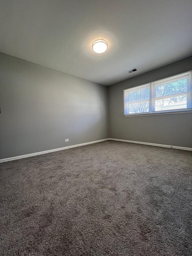 empty room featuring carpet, a healthy amount of sunlight, visible vents, and baseboards