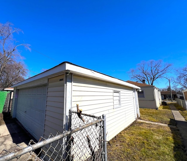 view of side of home featuring a garage, an outbuilding, and fence