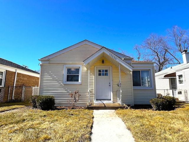 bungalow-style home with a front lawn and fence