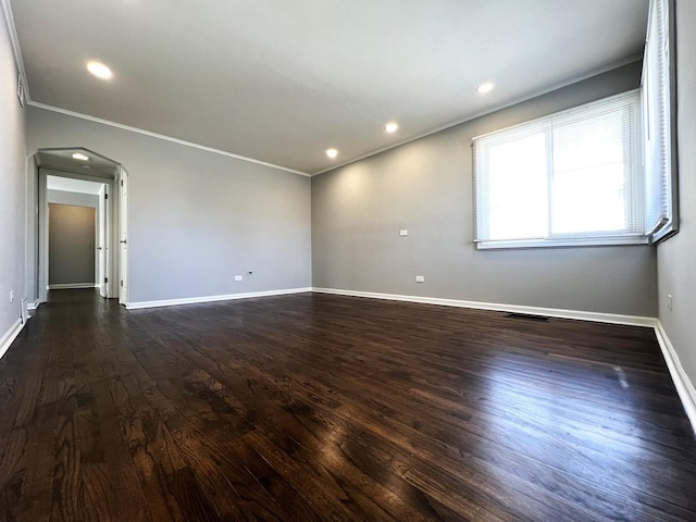 spare room with arched walkways, recessed lighting, baseboards, ornamental molding, and dark wood finished floors