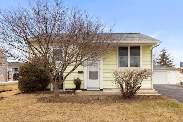 view of front of property featuring a garage, a front lawn, and roof with shingles