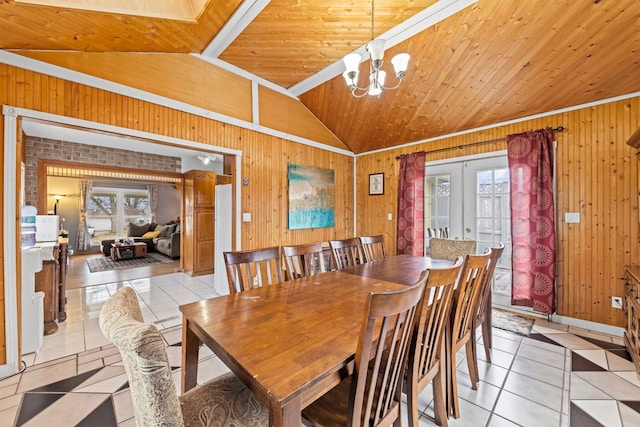 dining area featuring lofted ceiling, french doors, wood walls, and light tile patterned floors