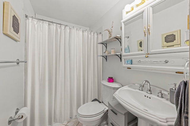 full bath with a shower with shower curtain, a sink, toilet, and tile patterned floors