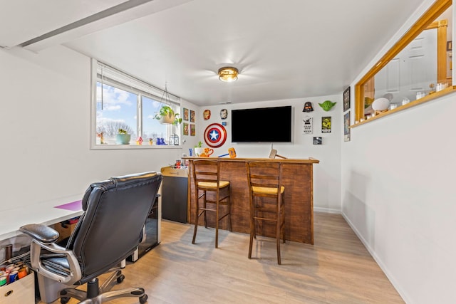 office space with baseboards, a bar, and wood finished floors