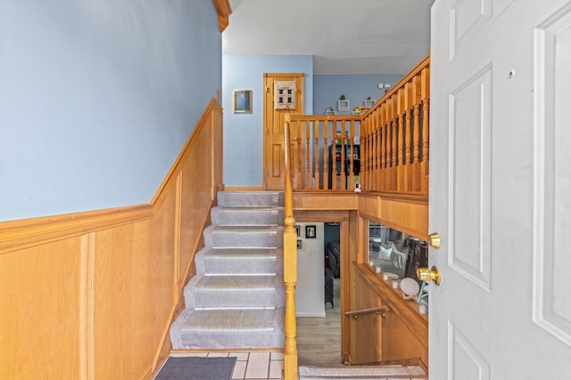 stairs with a wainscoted wall and wood finished floors