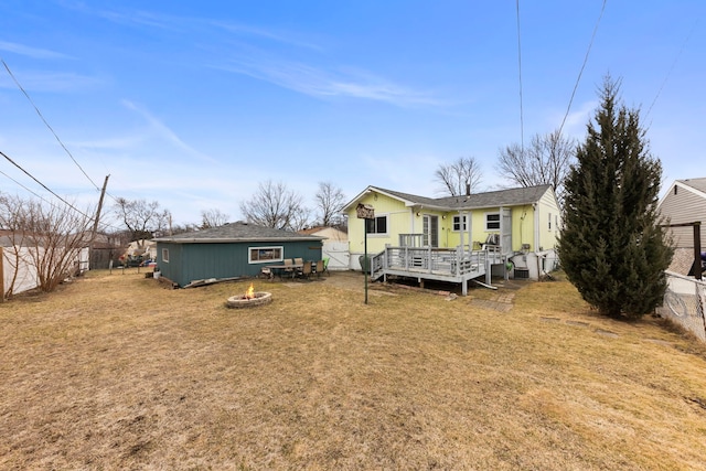 back of property featuring a yard, fence, a fire pit, and a wooden deck