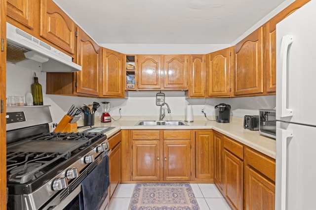 kitchen featuring light tile patterned floors, appliances with stainless steel finishes, light countertops, under cabinet range hood, and a sink