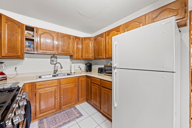 kitchen featuring appliances with stainless steel finishes, brown cabinets, a sink, and light tile patterned floors