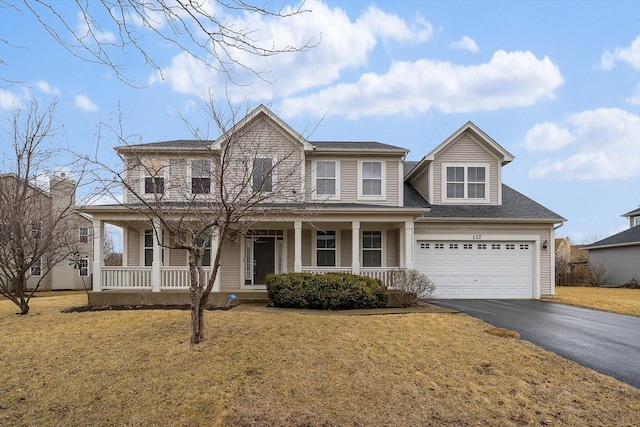 view of front of house with covered porch, driveway, a front lawn, and a garage