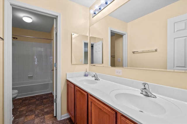 bathroom with stone finish flooring, a sink, toilet, and double vanity