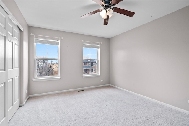 unfurnished bedroom featuring carpet, a closet, visible vents, ceiling fan, and baseboards