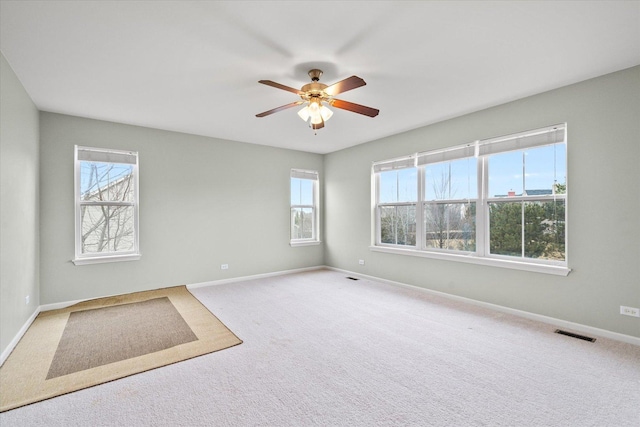 empty room with baseboards, visible vents, and a wealth of natural light