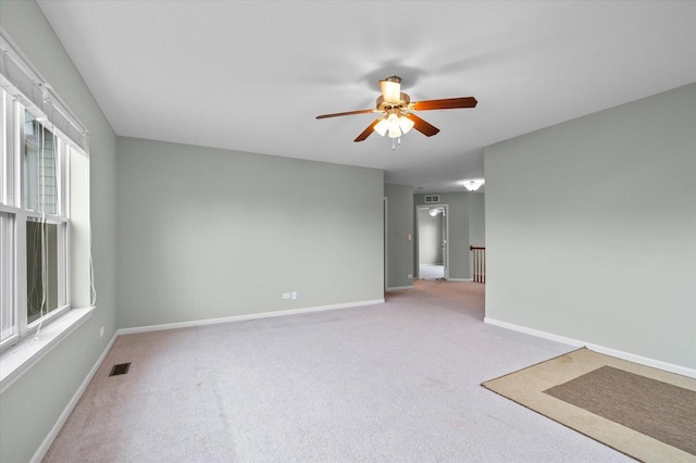 spare room featuring ceiling fan, carpet floors, visible vents, and baseboards