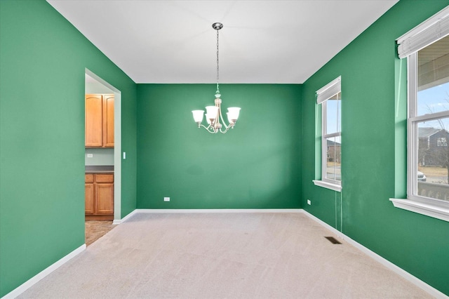 unfurnished room with baseboards, visible vents, a chandelier, and light colored carpet