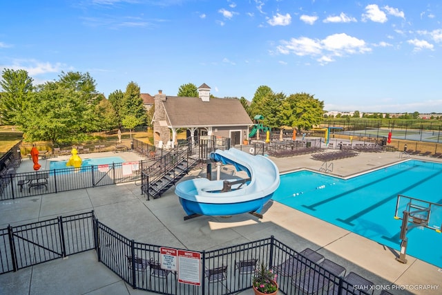 pool featuring a water slide, a patio area, fence, and an outdoor structure