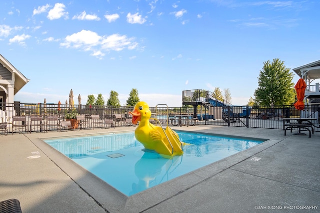 pool with a water play area, fence, and a patio