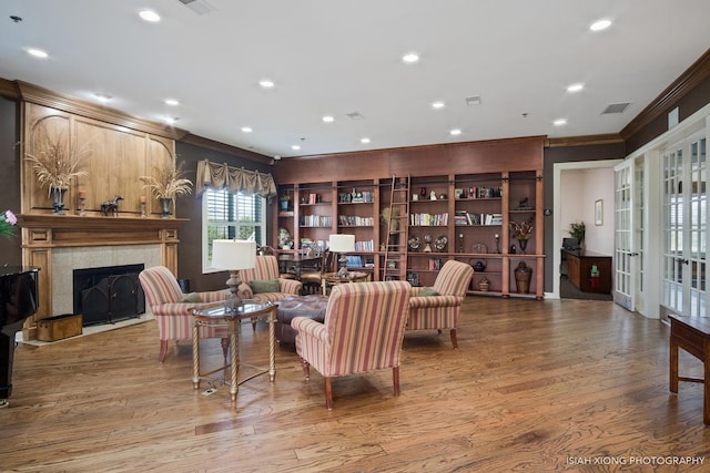 living area featuring a fireplace, crown molding, visible vents, and wood finished floors