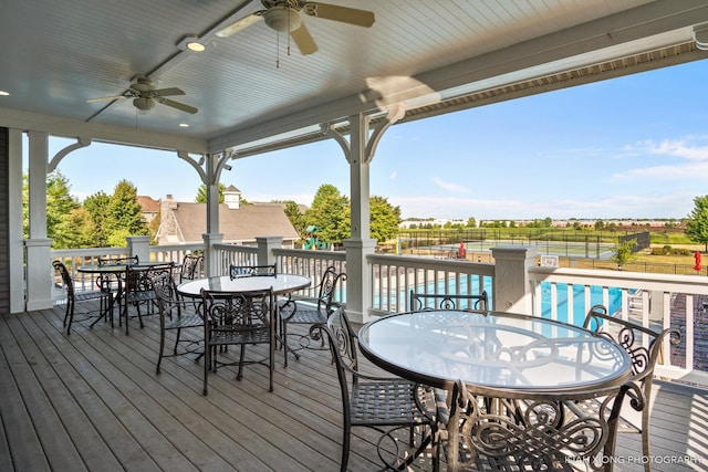 wooden terrace with ceiling fan, fence, and outdoor dining space