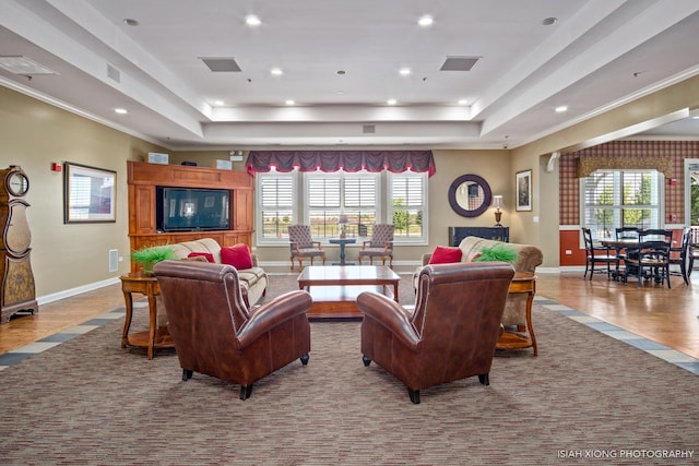 living room featuring a tray ceiling, visible vents, and baseboards