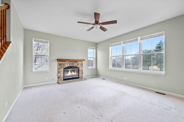 unfurnished living room with baseboards, carpet flooring, and a stone fireplace