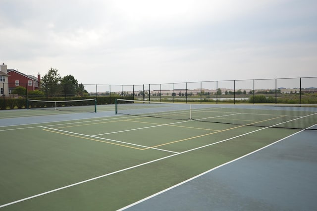 view of tennis court featuring community basketball court and fence