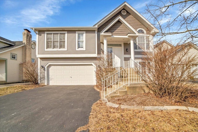 bi-level home featuring a garage and aphalt driveway