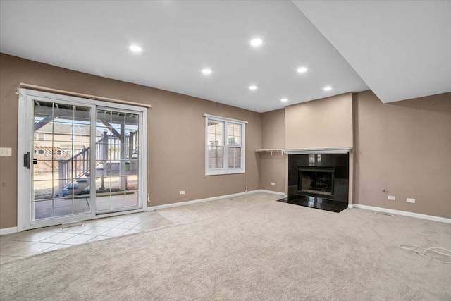 unfurnished living room featuring carpet floors, recessed lighting, baseboards, and a tiled fireplace