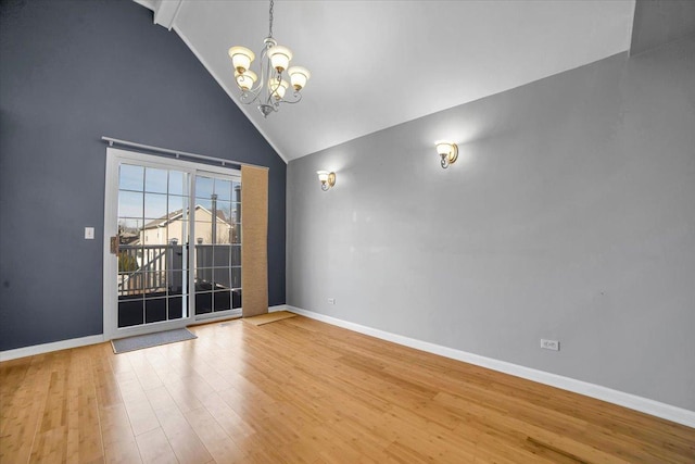 empty room with a chandelier, high vaulted ceiling, wood finished floors, and baseboards