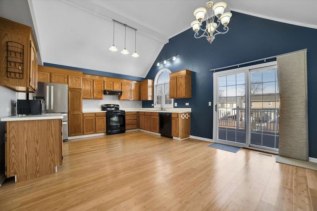 kitchen with black appliances, brown cabinetry, light countertops, and under cabinet range hood