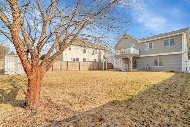 view of yard with a deck, a fenced backyard, stairway, and central AC unit