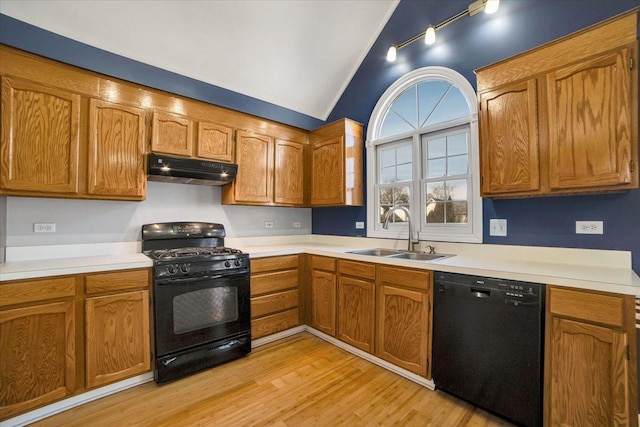 kitchen featuring lofted ceiling, light wood-style floors, a sink, under cabinet range hood, and black appliances